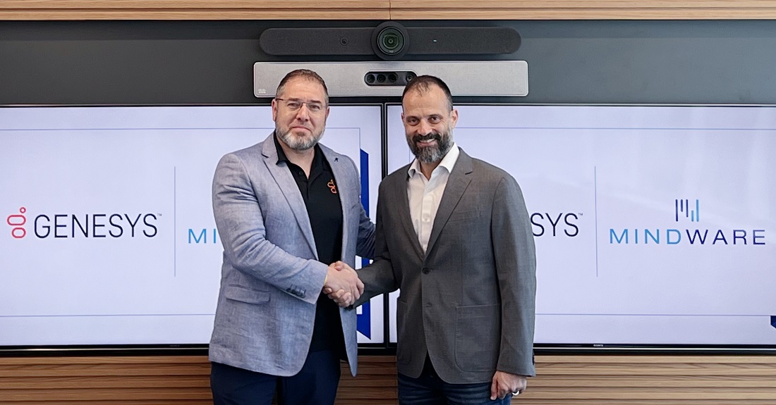 two men are shaking hands in front of a display with the names Mindware and Genesys in the background