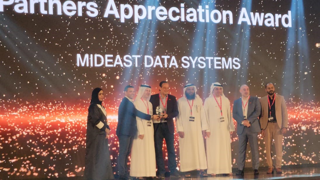 eight people are seen on a stage at a presentation as a trophy is awarded