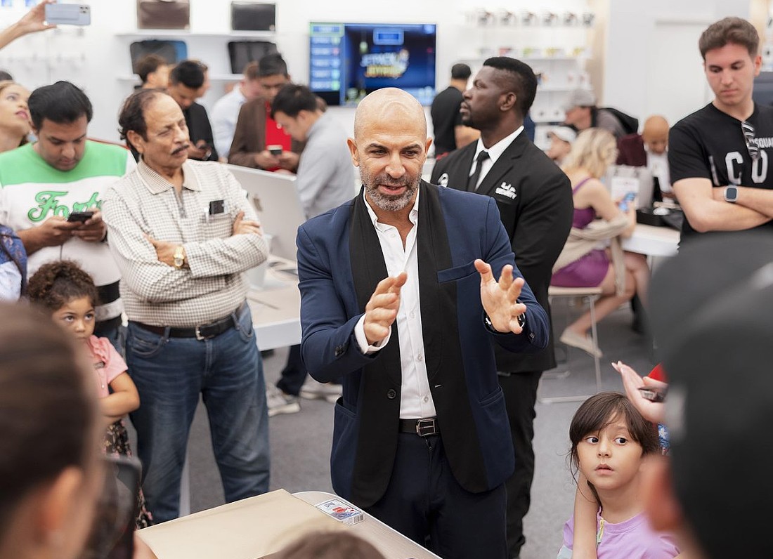 a man is seen center of the photo demonstrating a tech device to people. 