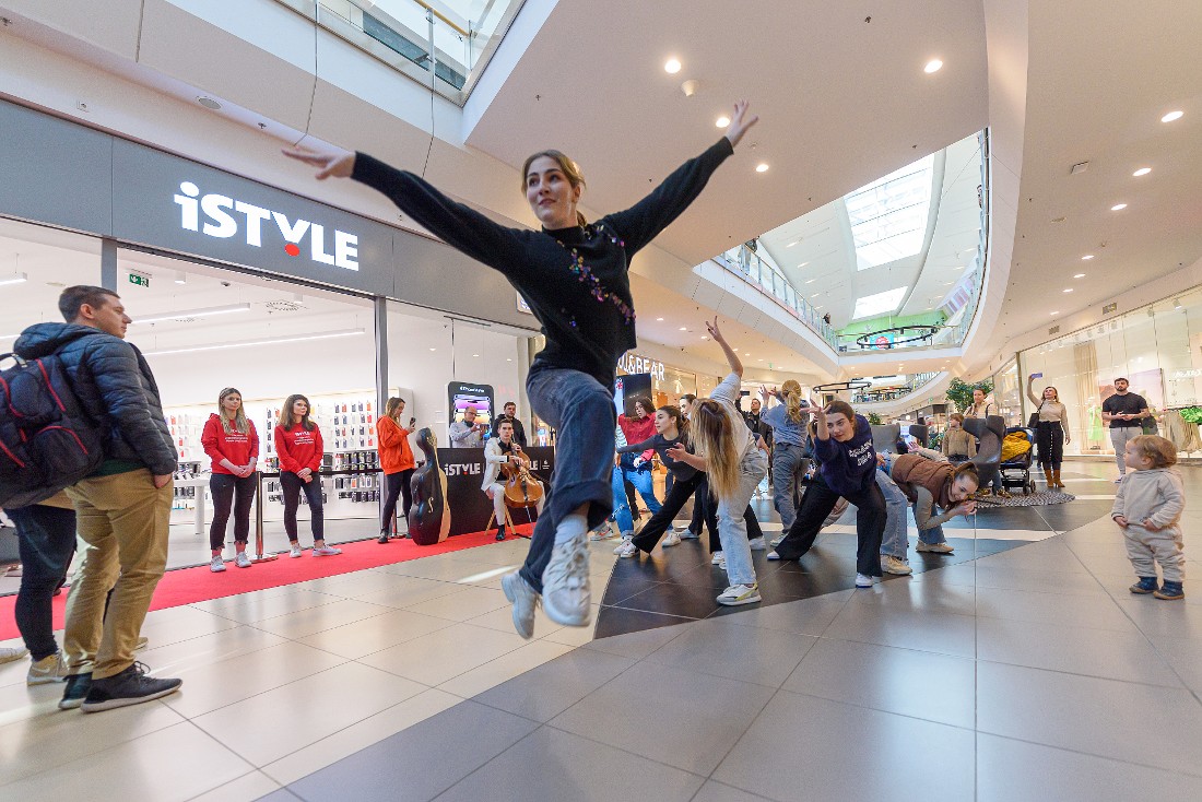 a female dancer leaps into the air outside the front of a hitech store