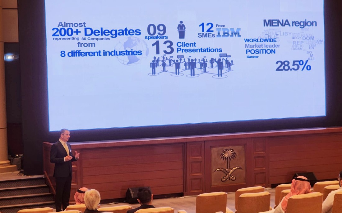 a man stands in front of an audience presenting in front of a digital screen