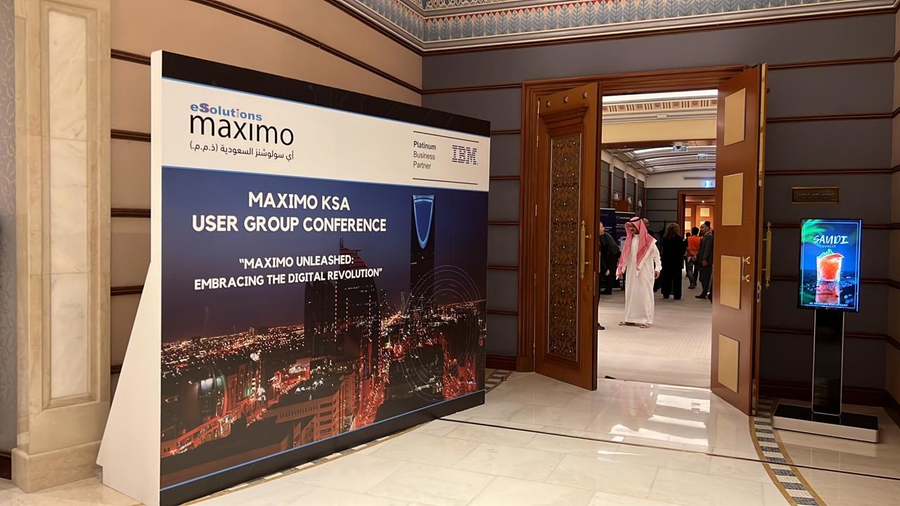 hall d'entrée pour la conférence du groupe d'utilisateurs Maximo avec un grand écran graphique à la gauche d'une porte