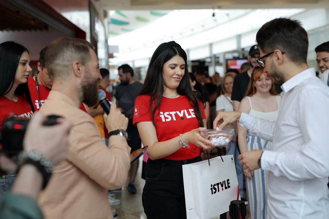 a woman in a red t-shirt is seen handing goods to customers in a hi-tech store