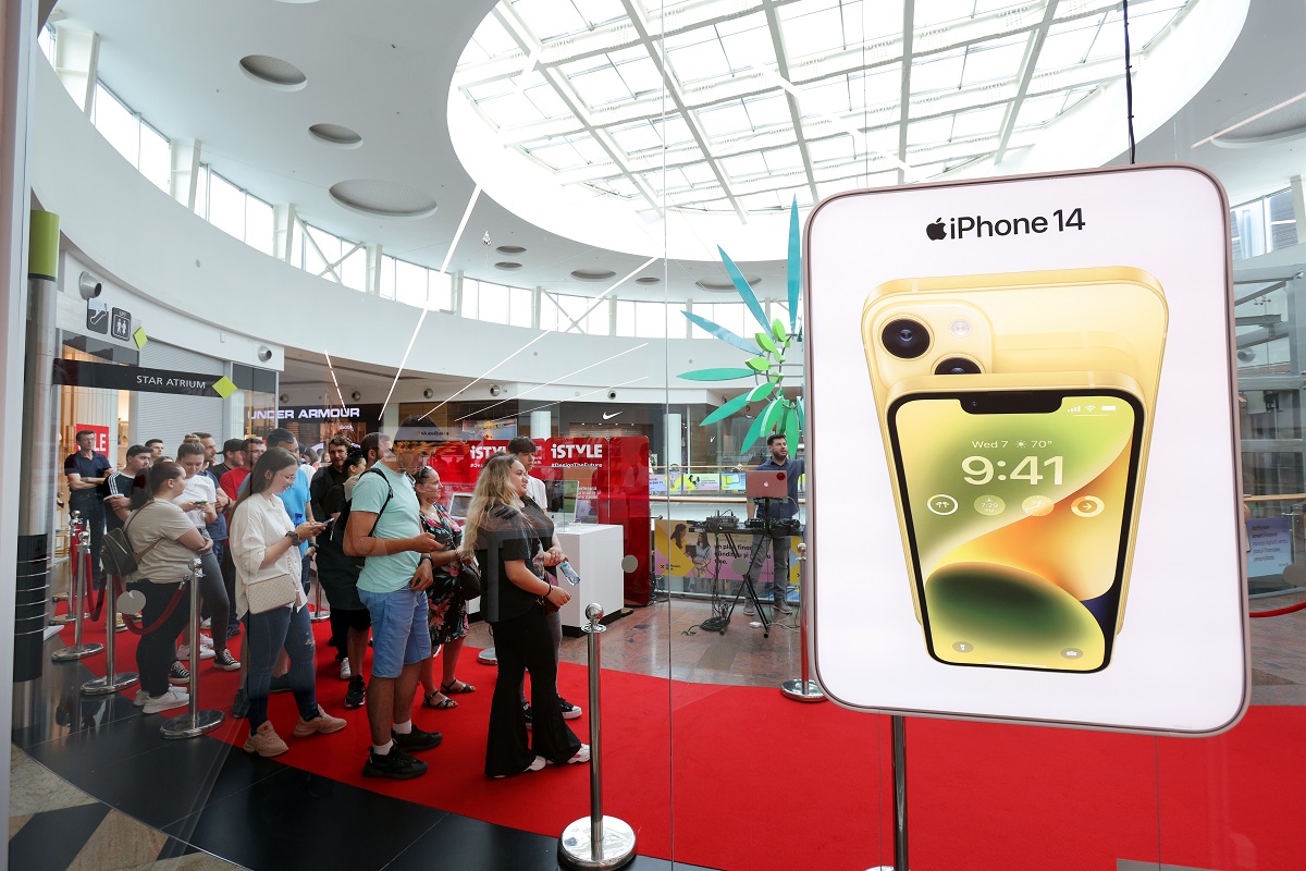 une file d'attente de personnes attend pour entrer dans un magasin de haute technologie avec des ordinateurs historiques vus à côté de la file