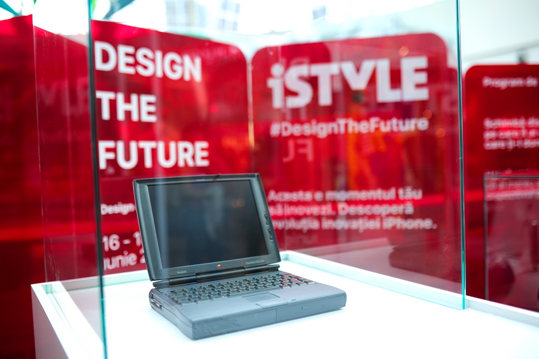 un grand modèle d'ordinateur portable Apple est présenté dans une boîte d'affichage en verre avec les mots Design the Future et iSTYLE bien en vue