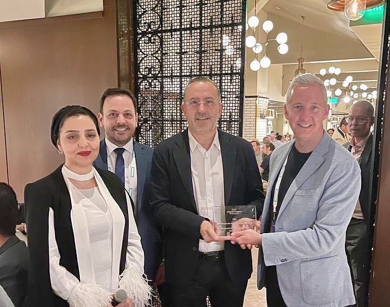 four people are seen together as a glass trophy is presented