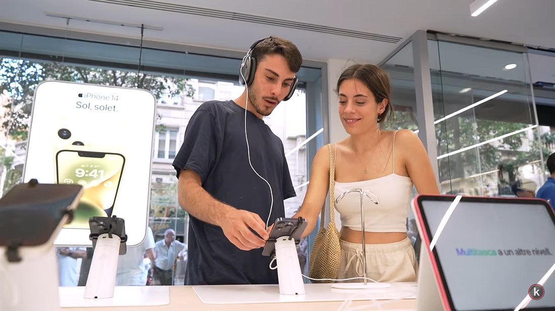 deux personnes regardent un téléphone Apple sur un site de vente au détail de haute technologie