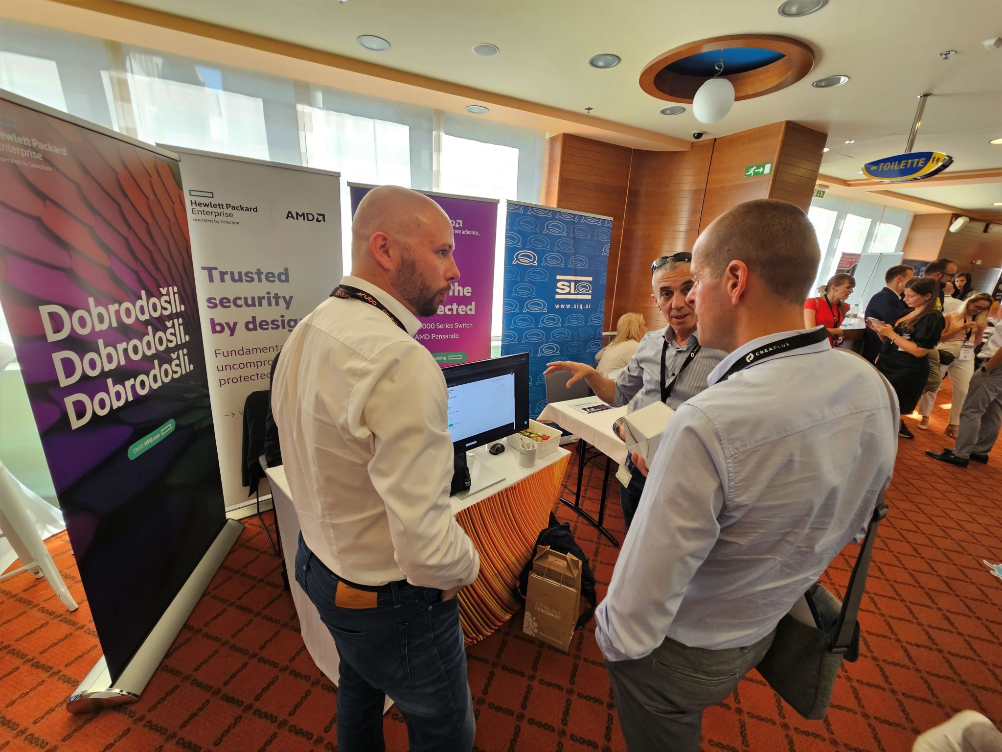 three men are talking together in front of an exhibition stand