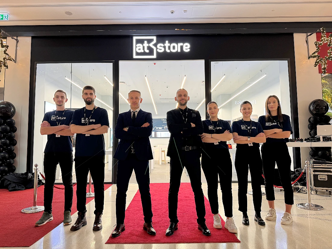 Seven people dressed in black stand in front of a hi tech store in a group photo