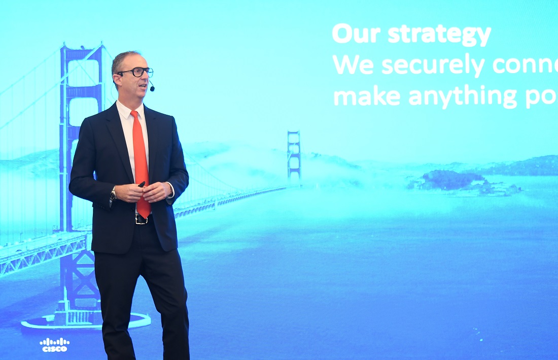 a man stands on a stage presenting in front of a blue screen