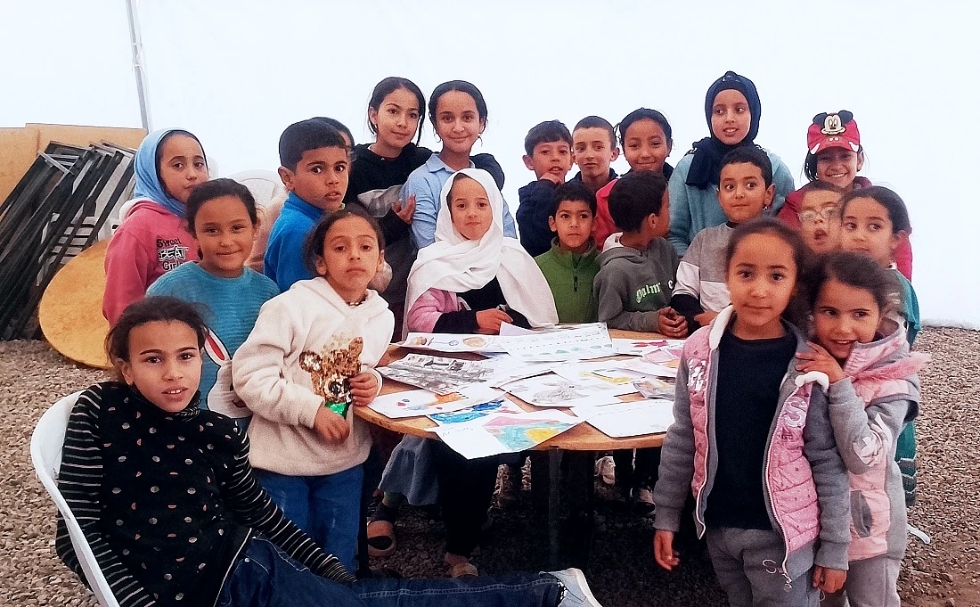 un grand groupe d'enfants se rassemblent autour d'une table