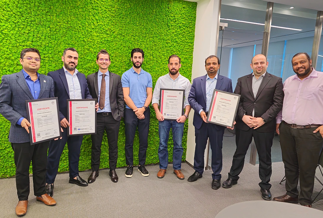 Eight men are seen in a group photo with four of them holding certificates