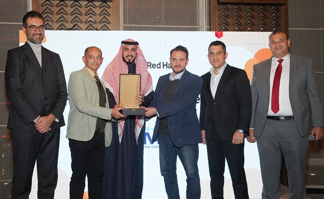 six men are seen on a presentation stage with a trophy being handed over.