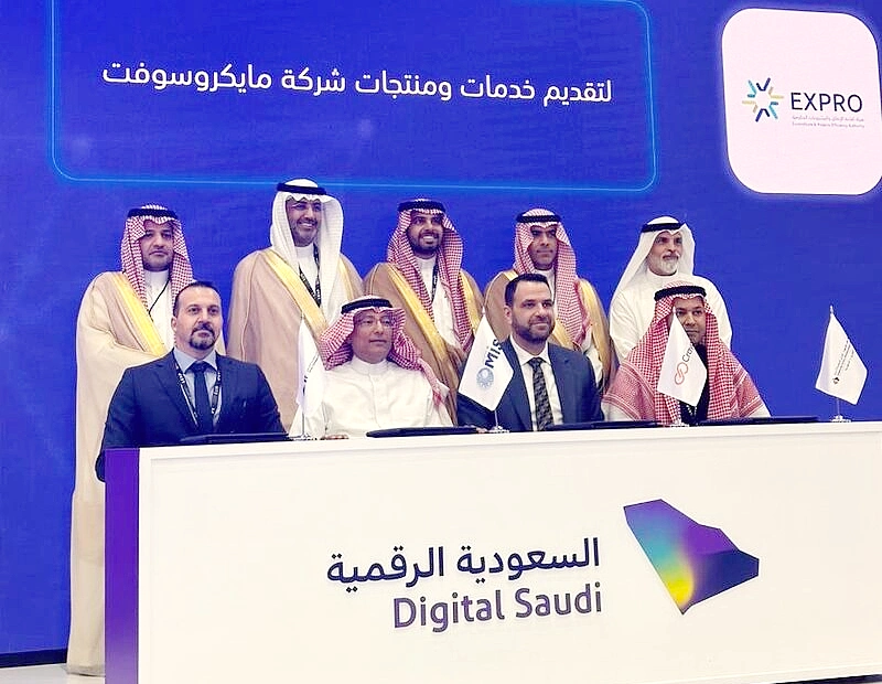 Neuf hommes sont vus sur une scène de présentation avec les mots Digital Saudi sur le bureau devant eux.