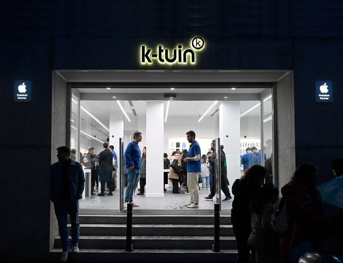 Exterior view at night of a hi tech store, with people visible inside