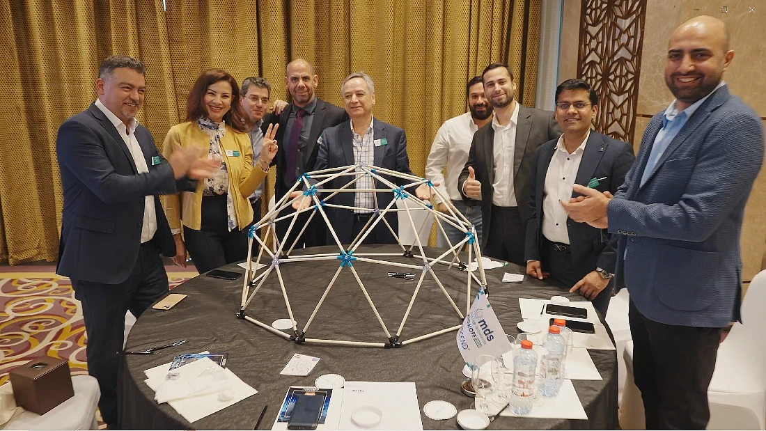 un groupe de personnes est vu autour d'une table après avoir terminé une tâche de construction d'un modèle de structure géométrique