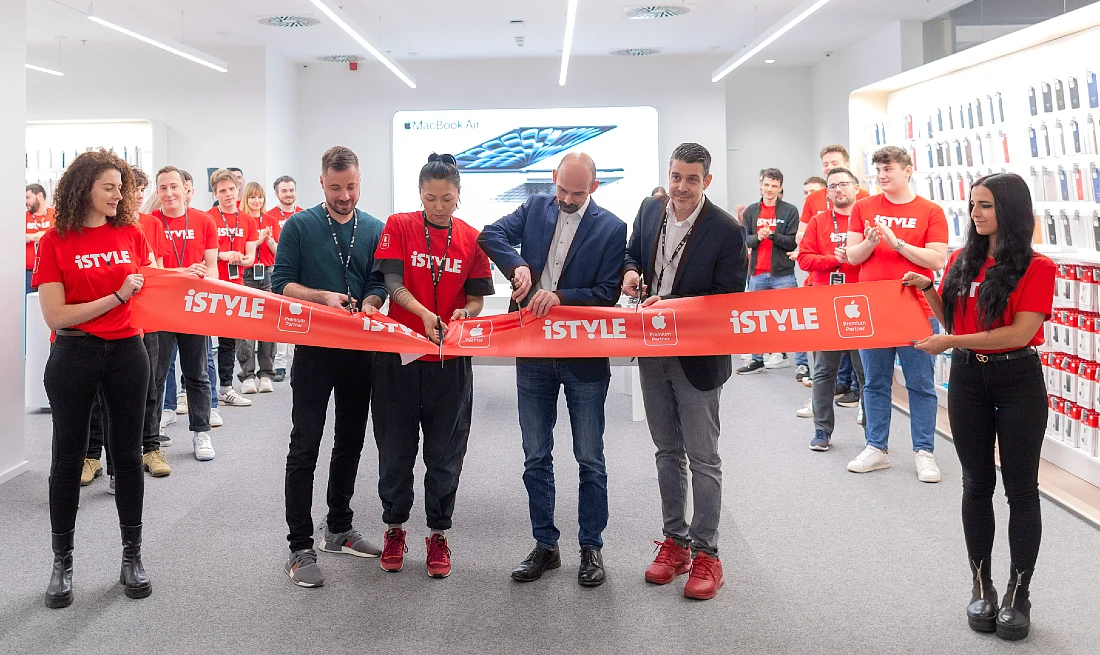 four people are seen cutting a red tape to open a hi tech store