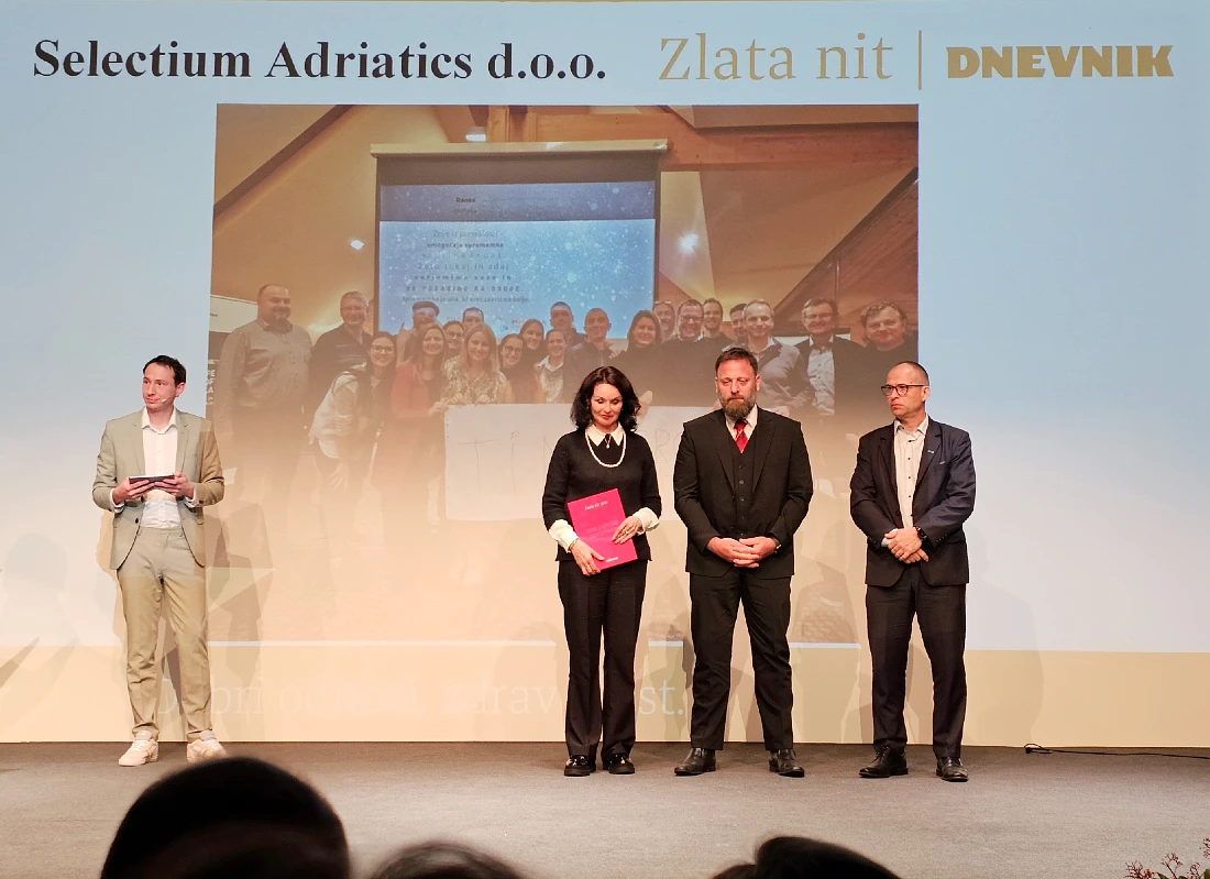 four people are seen on a presentation stage as one person announces a winner