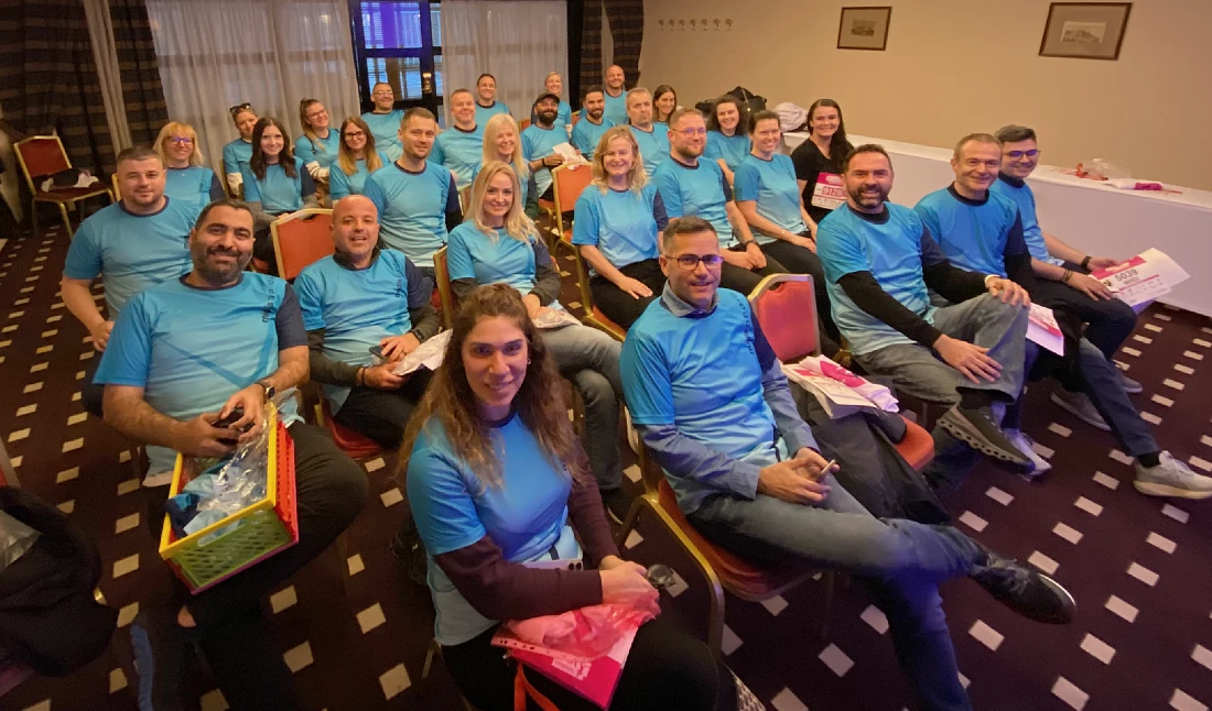 a large group of people assembled in a room wearing blue t-shirts