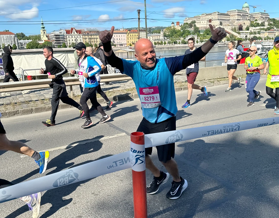 a man in a blue t-shirt runs past the viewer with his arms raised