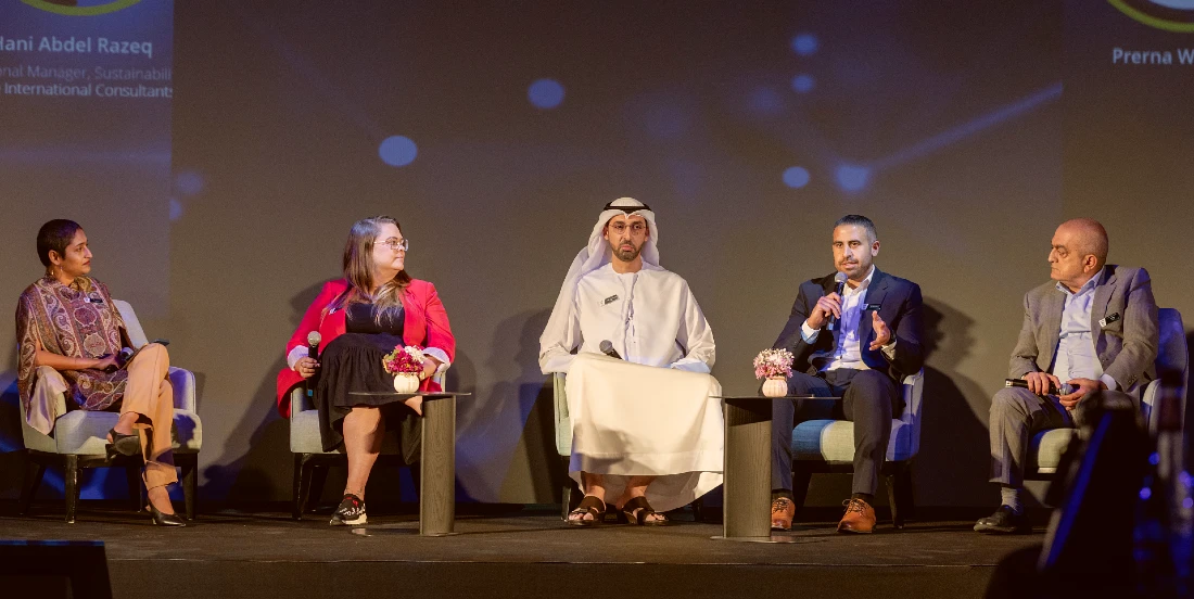 five people are sitting on a stage in a panel discussion