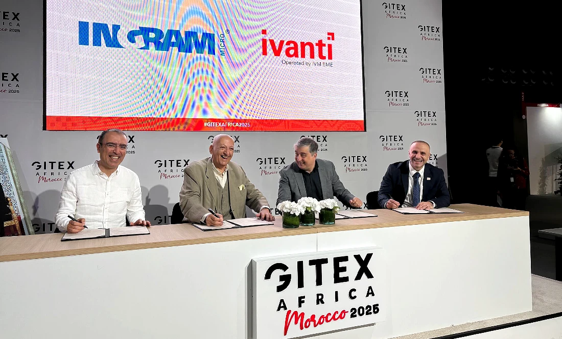 Four men are seen at a signing ceremony, with logos seen behind them on a screen