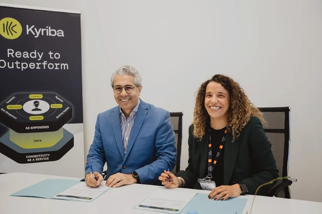 two people sit at a desk and are seen having just signed an agreement