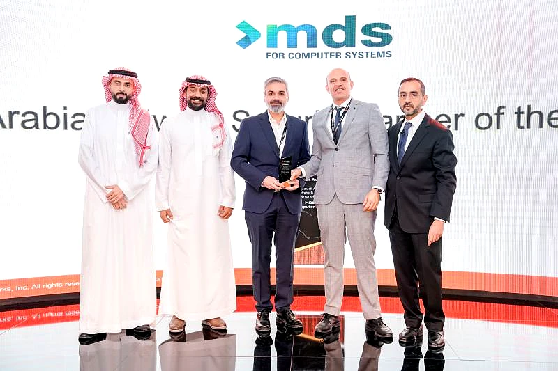 five men are seen on a presentation stage as a trophy is handed over. 