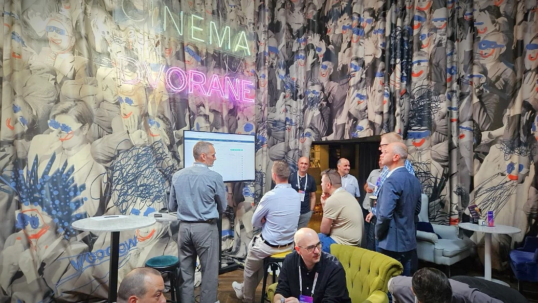 Six people seen at a hi tech event looking at a computer screen on the wall