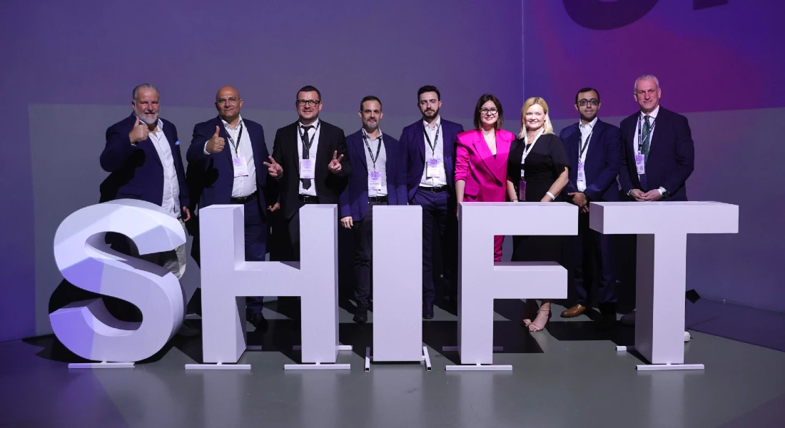 Group photo of seven people in suits standing next to giant letters spelling the word, shift