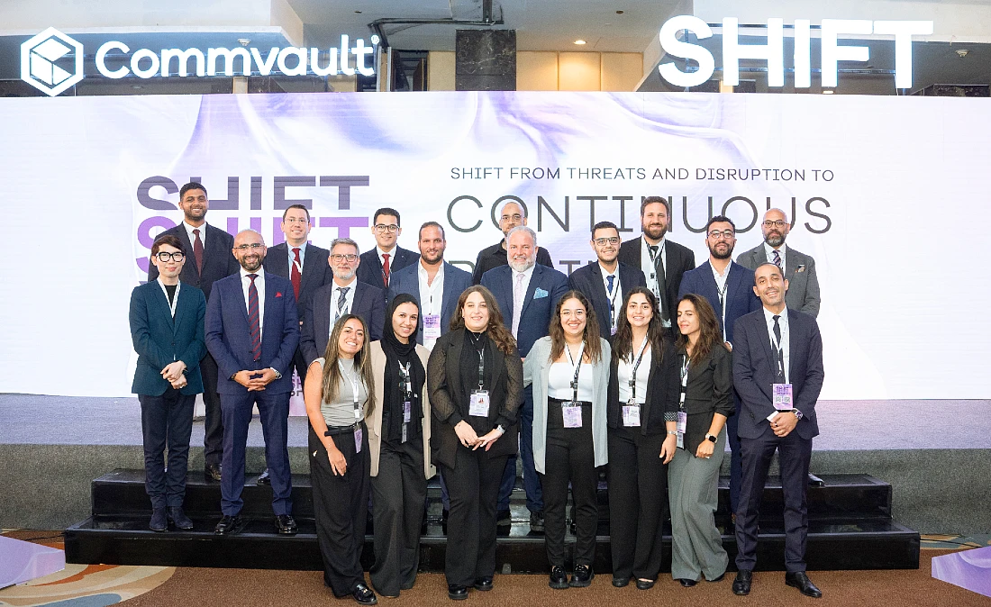 a large group of people seen smiling in a group photograph in front of a presentation stage