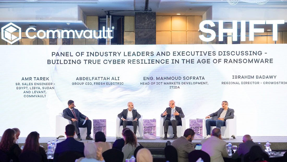 Four men are seen on a stage taking part in a panel discussion