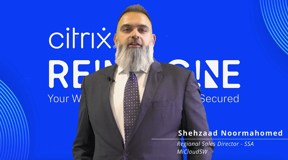 a bearded man in a suit is seen speaking in front of a blue background in this video screenshot