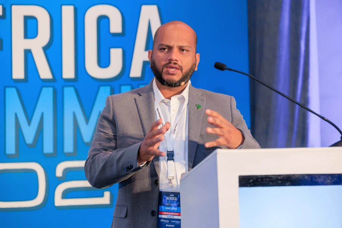 A man is seen in close up presenting to an audience - he is gesturing with his hands 