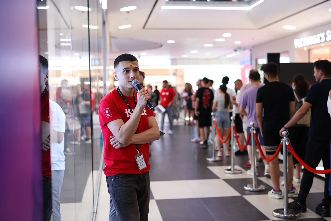 a man talks into a mic while addressing the queue of visitors to the new store
