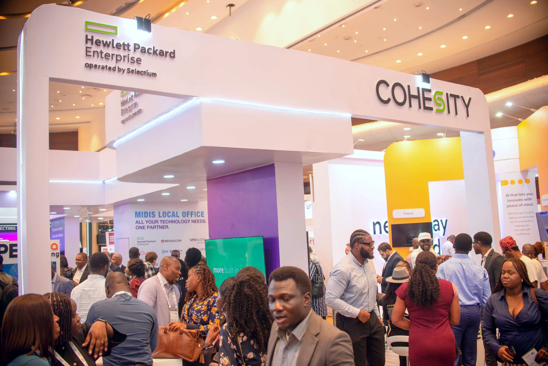a hi tech exhibition stand at an event in Africa - many people are seen talking in the foreground