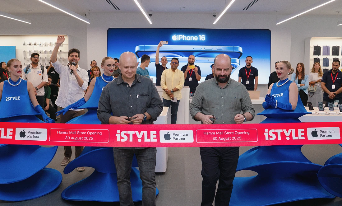 Two men at an IT store opening event stand ready to cut a red tape to open the store