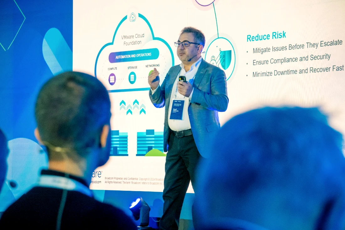 A man in a suit jacket presents to an audience at a hi tech event