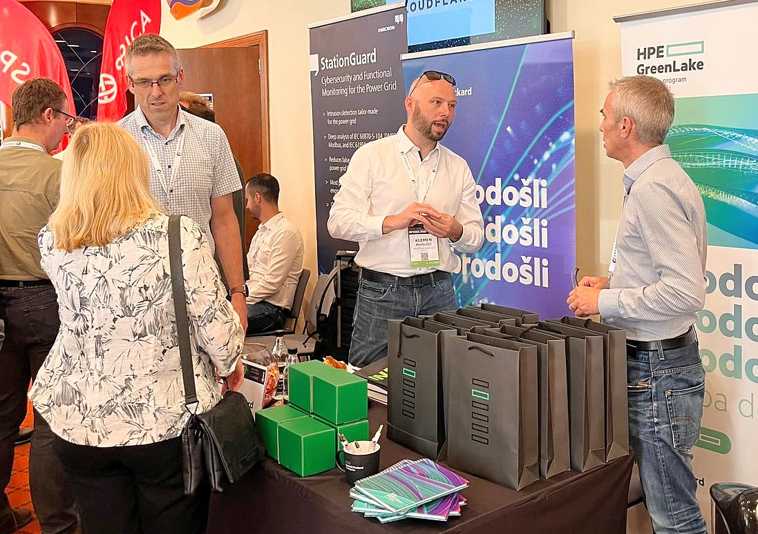 People are seen talking at a booth at a hi tech event