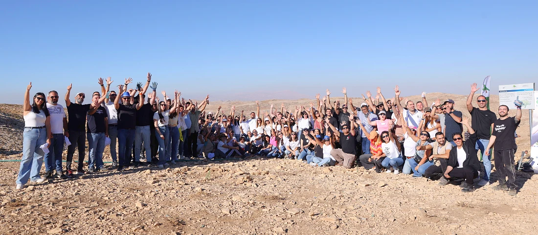 Un grand groupe de personnes est rassemblé dehors au soleil pour une photo de groupe.