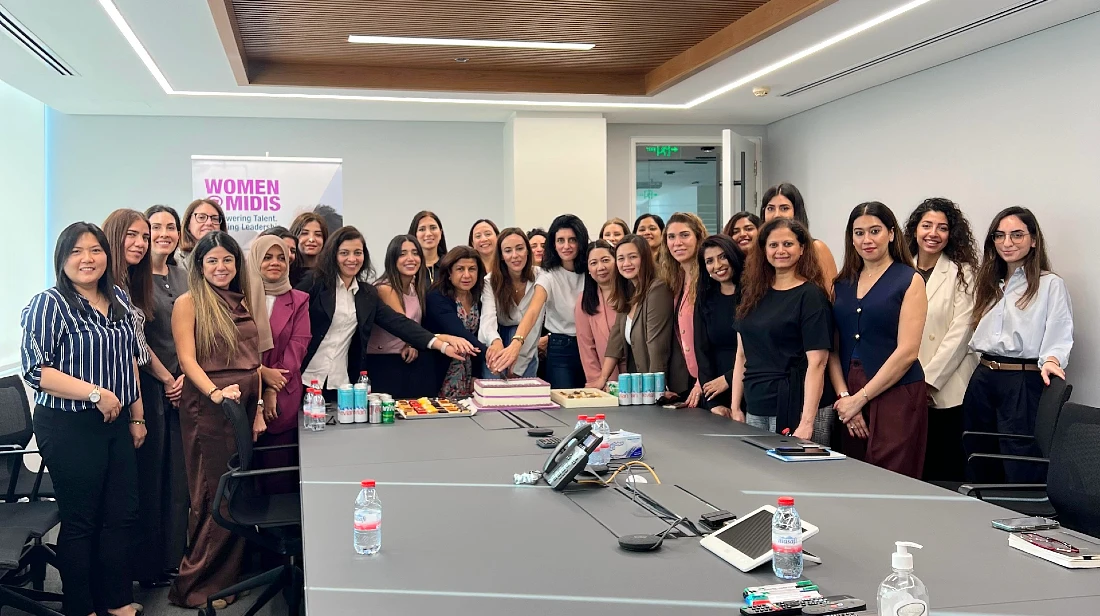A group of women are seen in an office setting in a group photograph