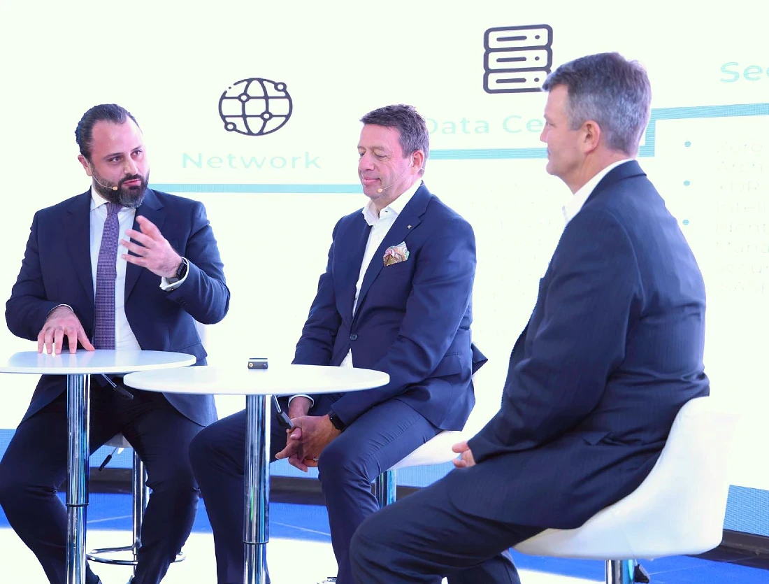 Three men are seen on stage at a hi-tech event having a discussion