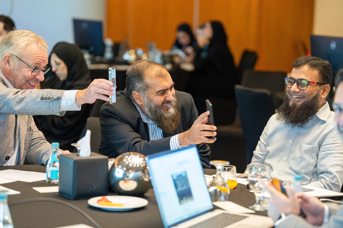 three men at a hi tech event are seen looking at mobile phones at a hi tech event