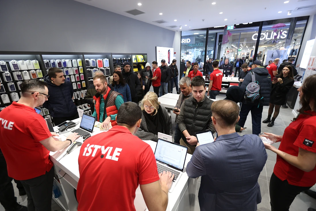 a busy scene at the opening of a hi-tech store with customers and store team members talk about the apple products on offer 