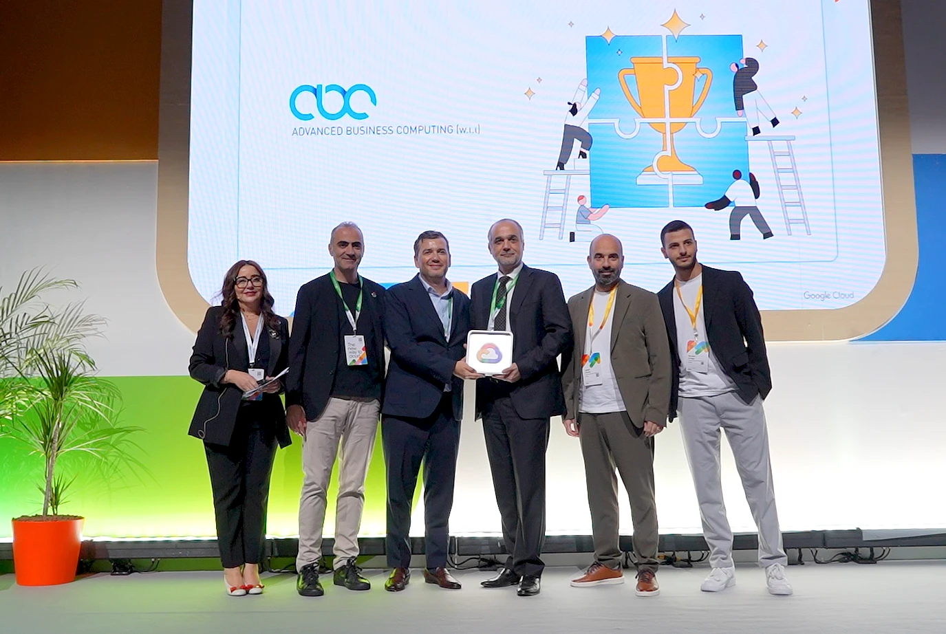 six people stand on stage to accept an award trophy