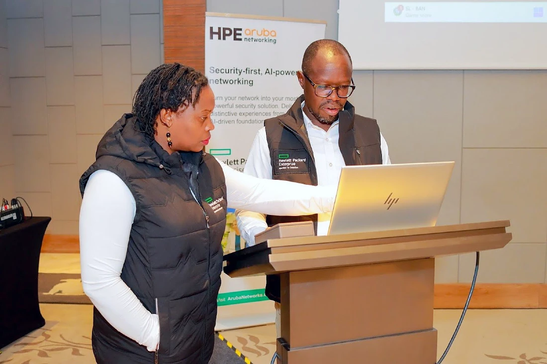 Two people are seen looking at a presentation laptop on a hi-tech event stage