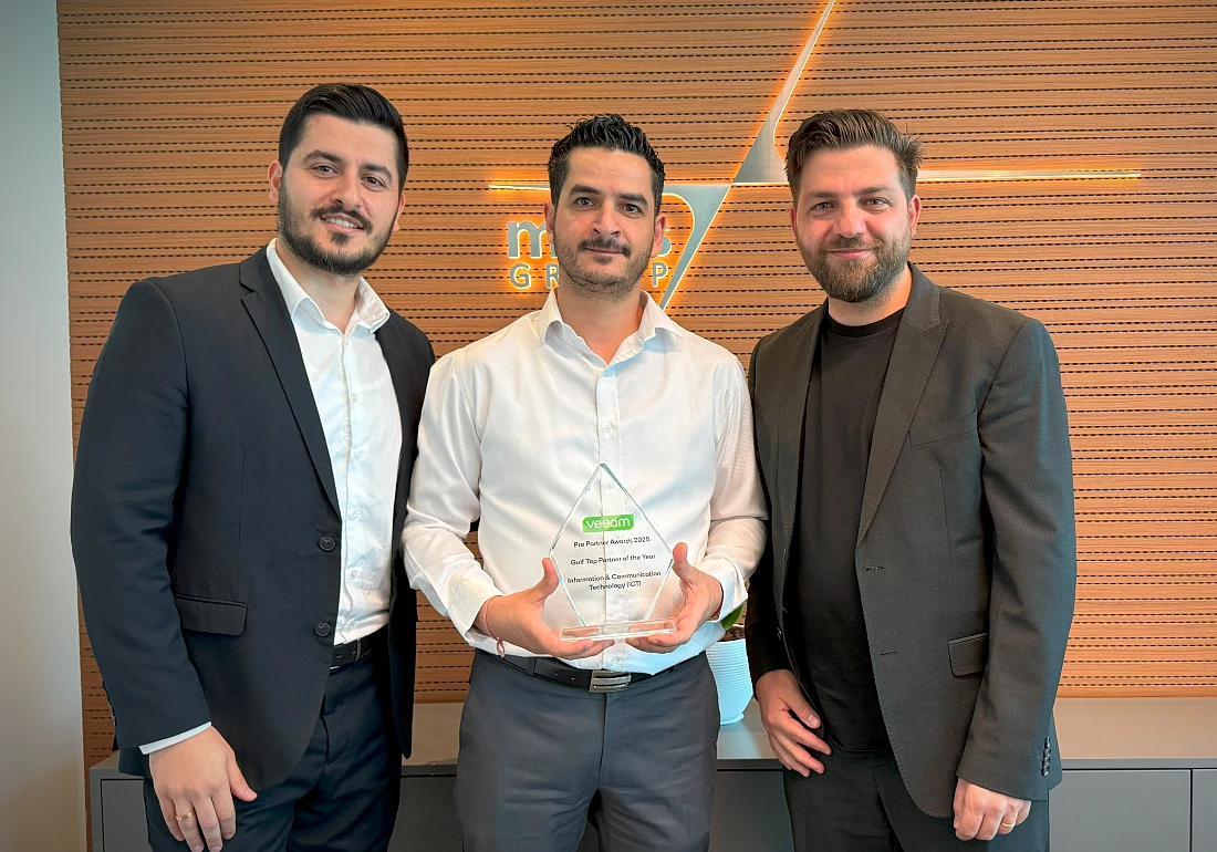 Three men are seen with the central figure holding a trophy