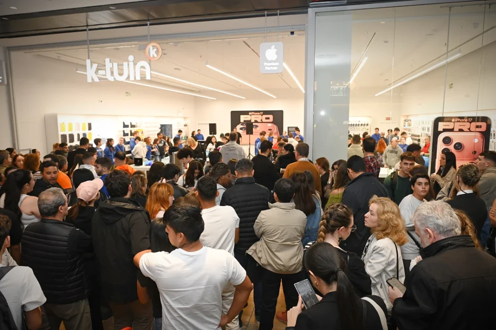 A large crowd of people are seen at the front of a hi tech store