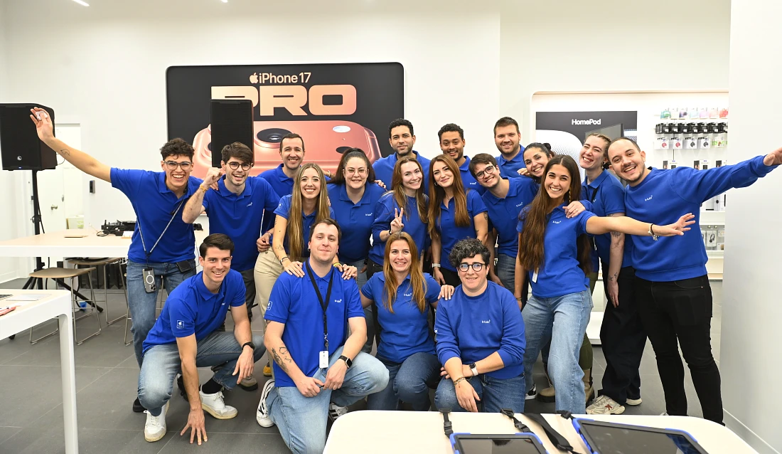 a group of people in blue t shirts in a smiling photo in a hi tech store