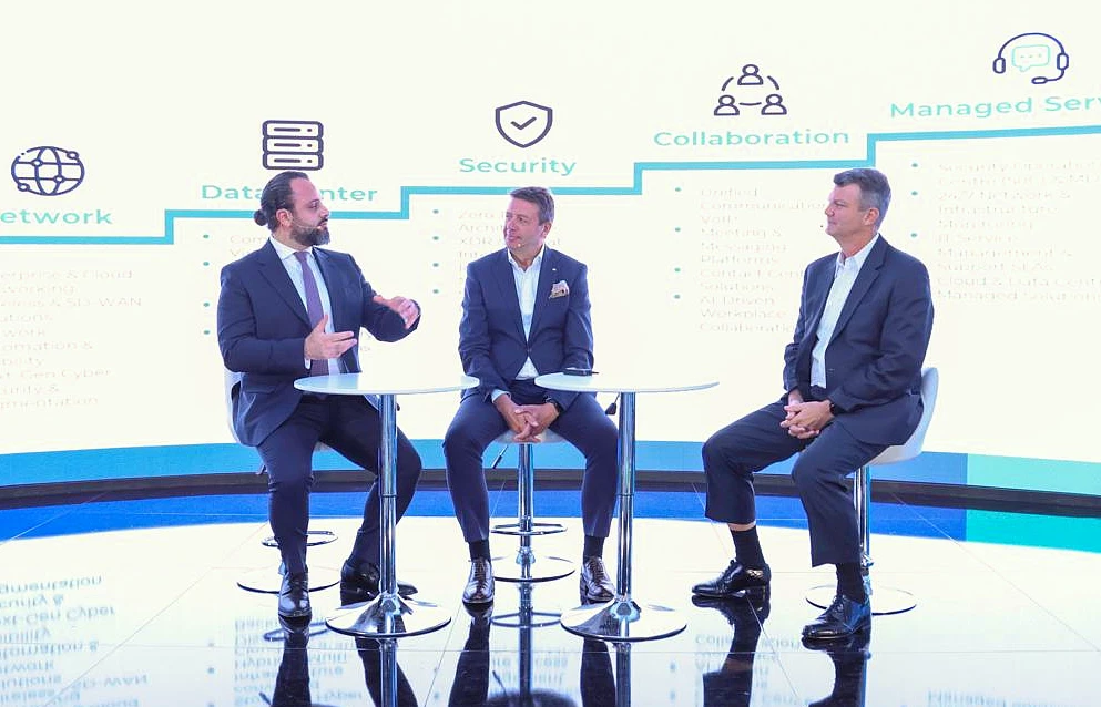 Three men are seen on stage at a hi tech event having a discussion